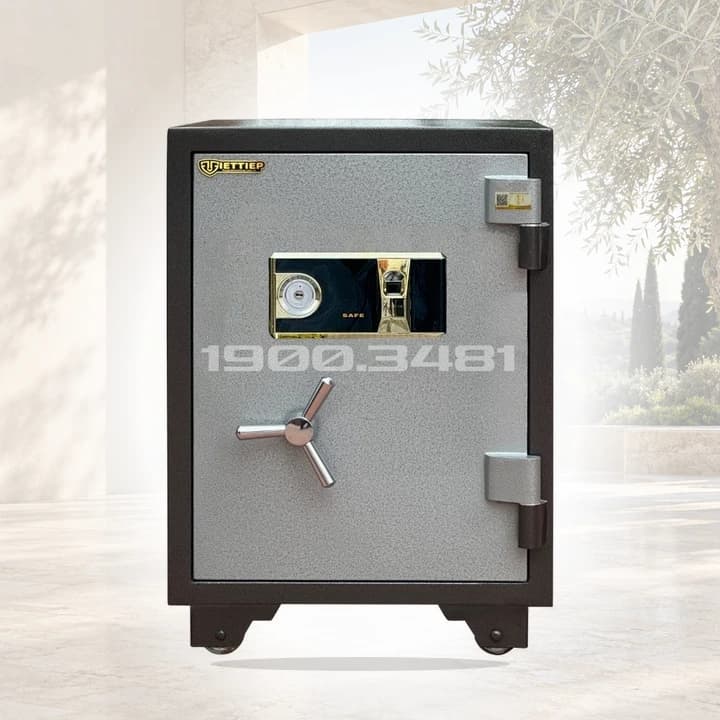 Két Sắt SC600 FG - Khóa Vân Tay Cảm Biến trong kiến trúc đá sáng và khu vườn xanh, ảnh ghép bối cảnh AI.